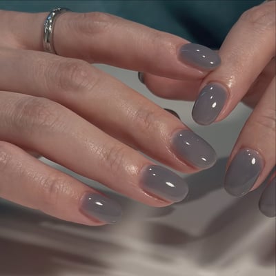 Oval, medium-length nails with a glossy, translucent grayish-blue gel polish.
