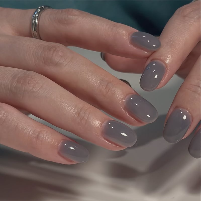 Oval, medium-length nails with a glossy, translucent grayish-blue gel polish.