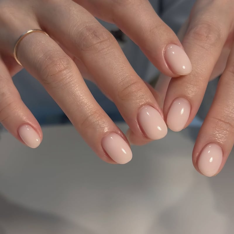 Oval nails with a sheer, milky pink gel polish and a glossy finish.